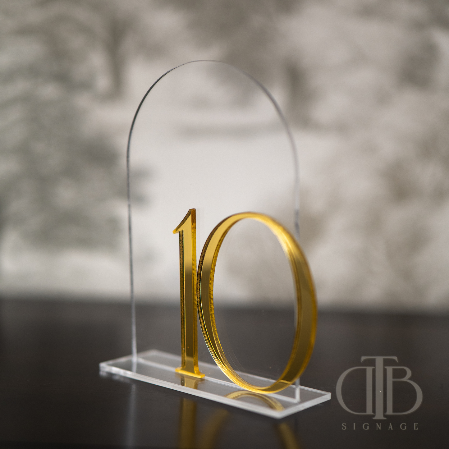 Gold number '10' on a clear stand with a blurred background