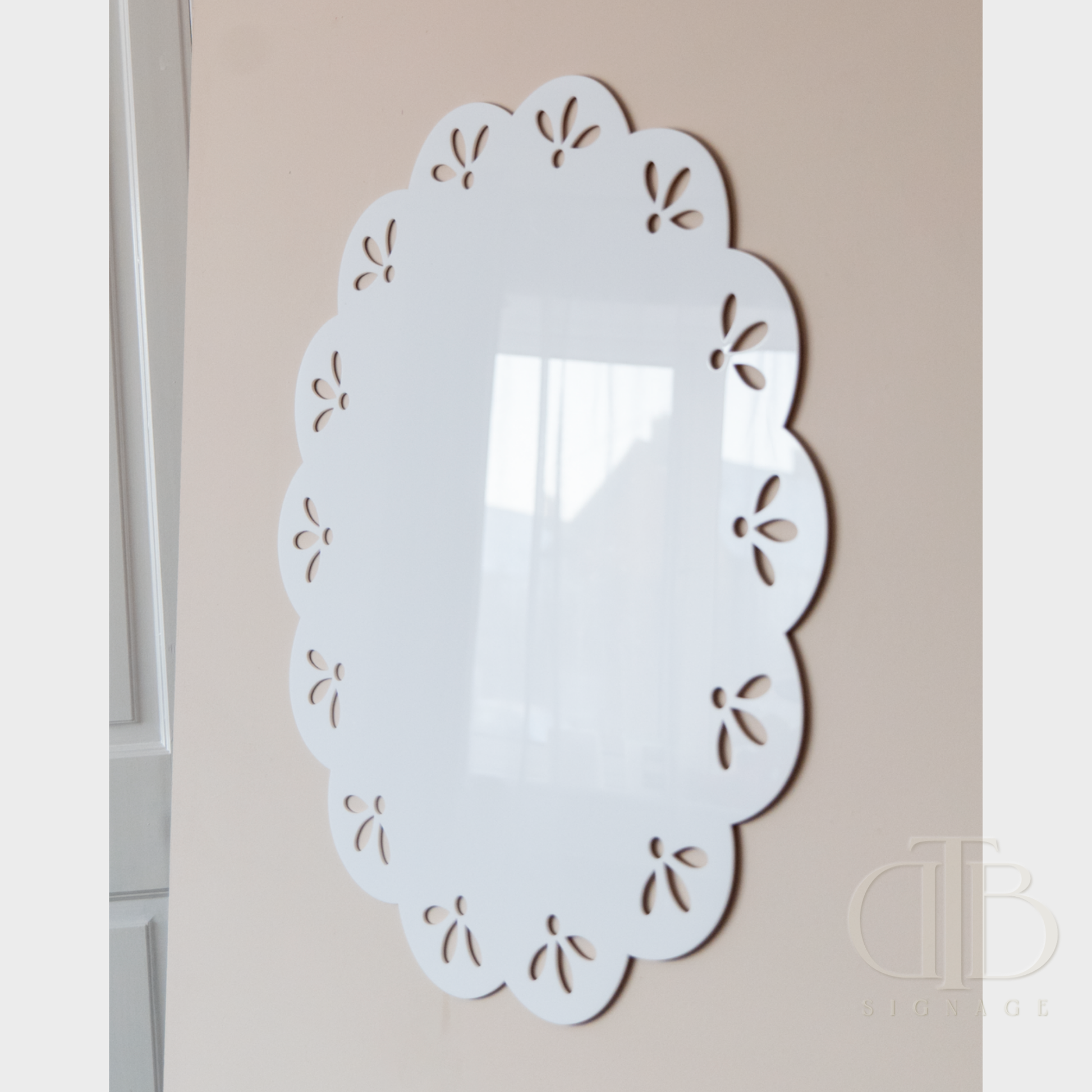 Decorative white acrylic signage with cut-out patterns on a beige wall