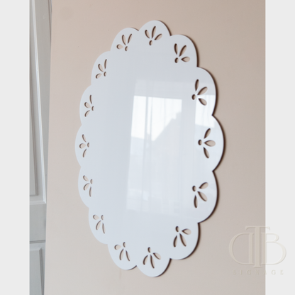 Decorative white acrylic signage with cut-out patterns on a beige wall