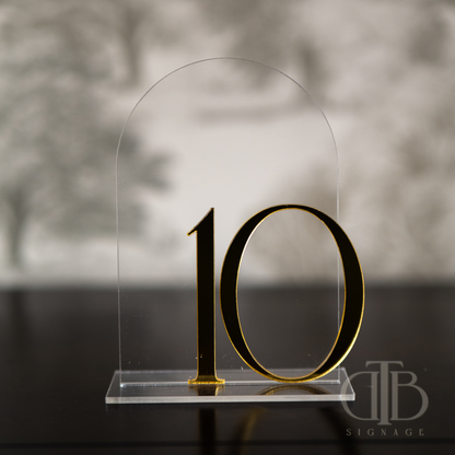Gold number '10' on a clear acrylic stand with a blurred background