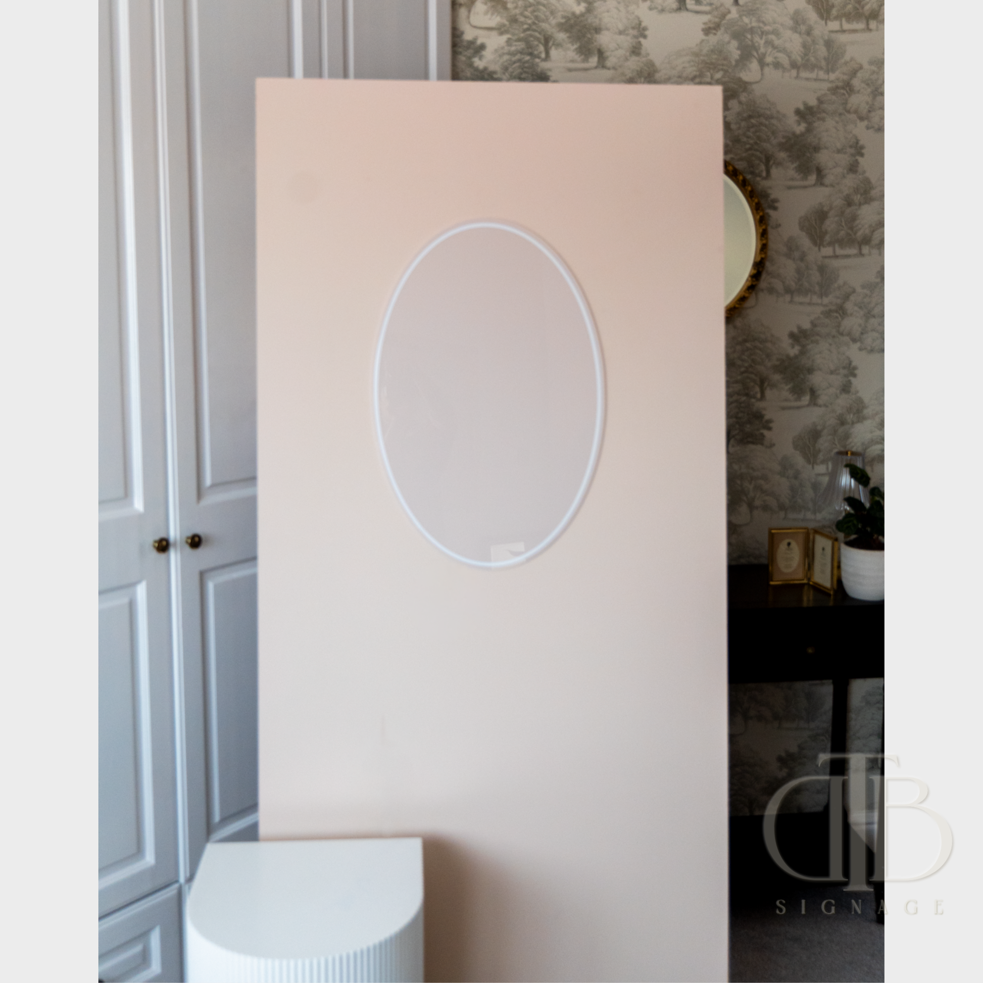 Pink wall with a round acrylic in a room with patterned wallpaper