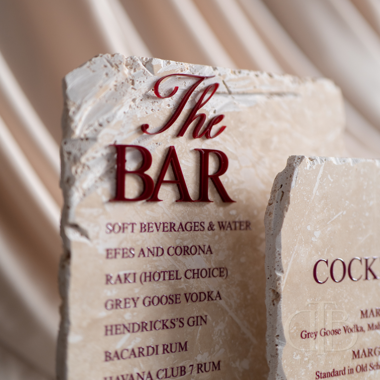 Stone menu board with 'The Bar' and drink options on a draped fabric background