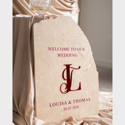 Decorative stone with 'Welcome to our wedding' text and monogram on a draped fabric background