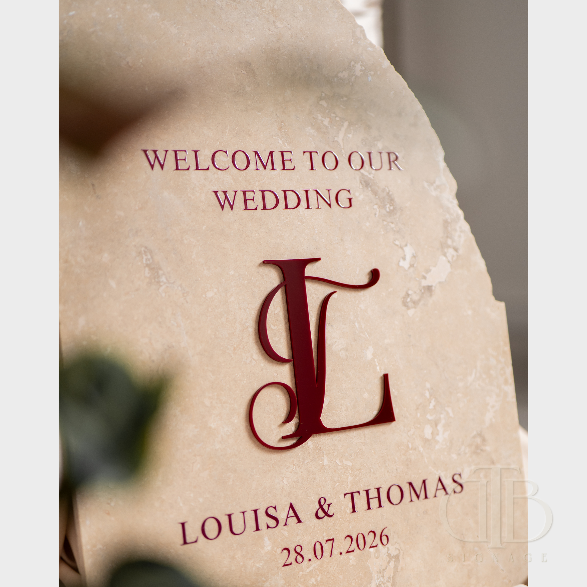 Wedding invitation card with 'Welcome to our wedding' text and monogram on a stone background.