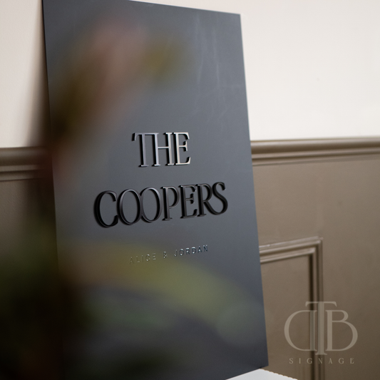 Black sign with 'The Coopers' on a wall, featuring the logo of DTB Signage.