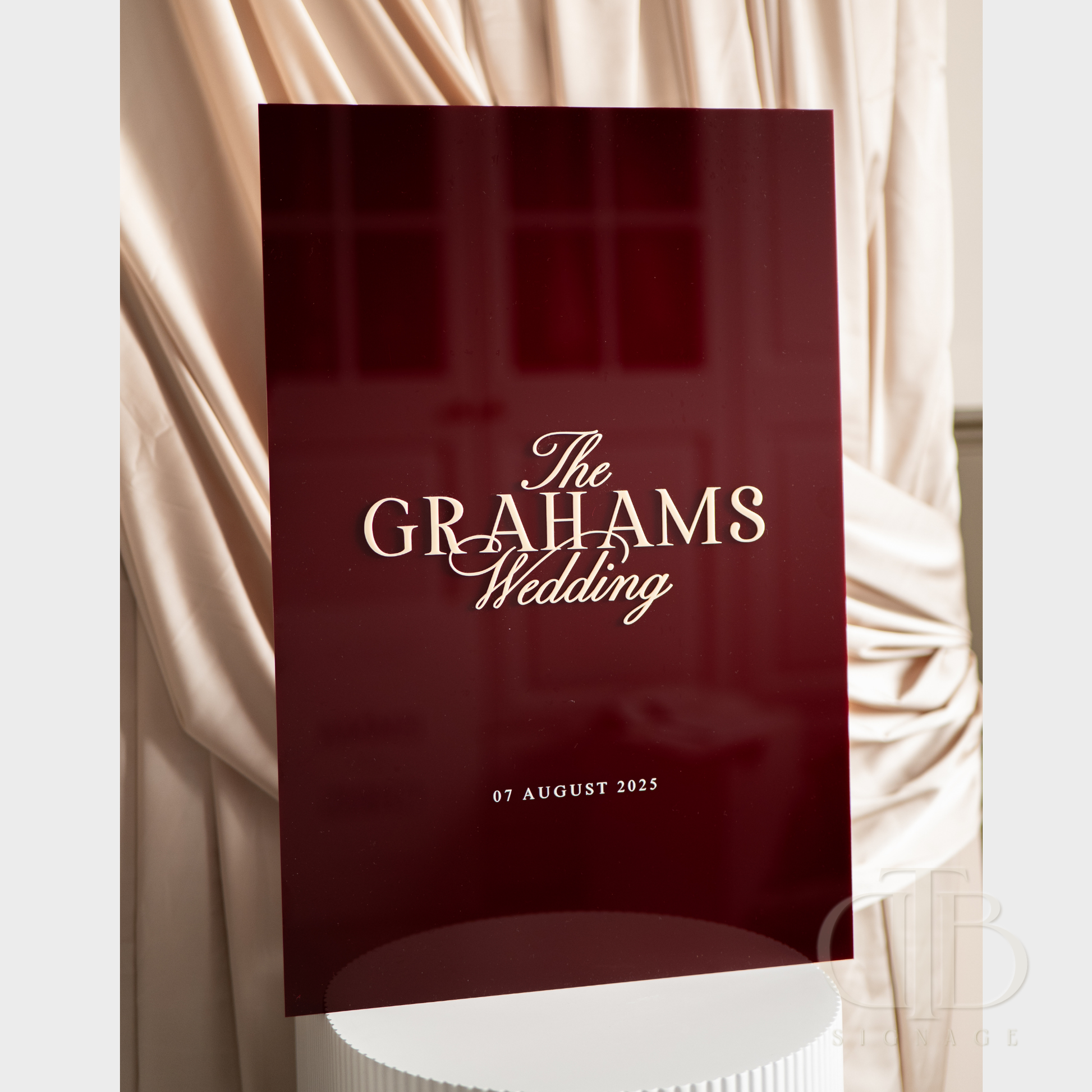 Red wedding invitation with 'The Grahams Wedding' text against a draped fabric background