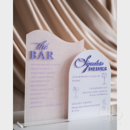 Acrylic sign with 'The Bar' and 'Signature Drinks' text on a draped fabric background