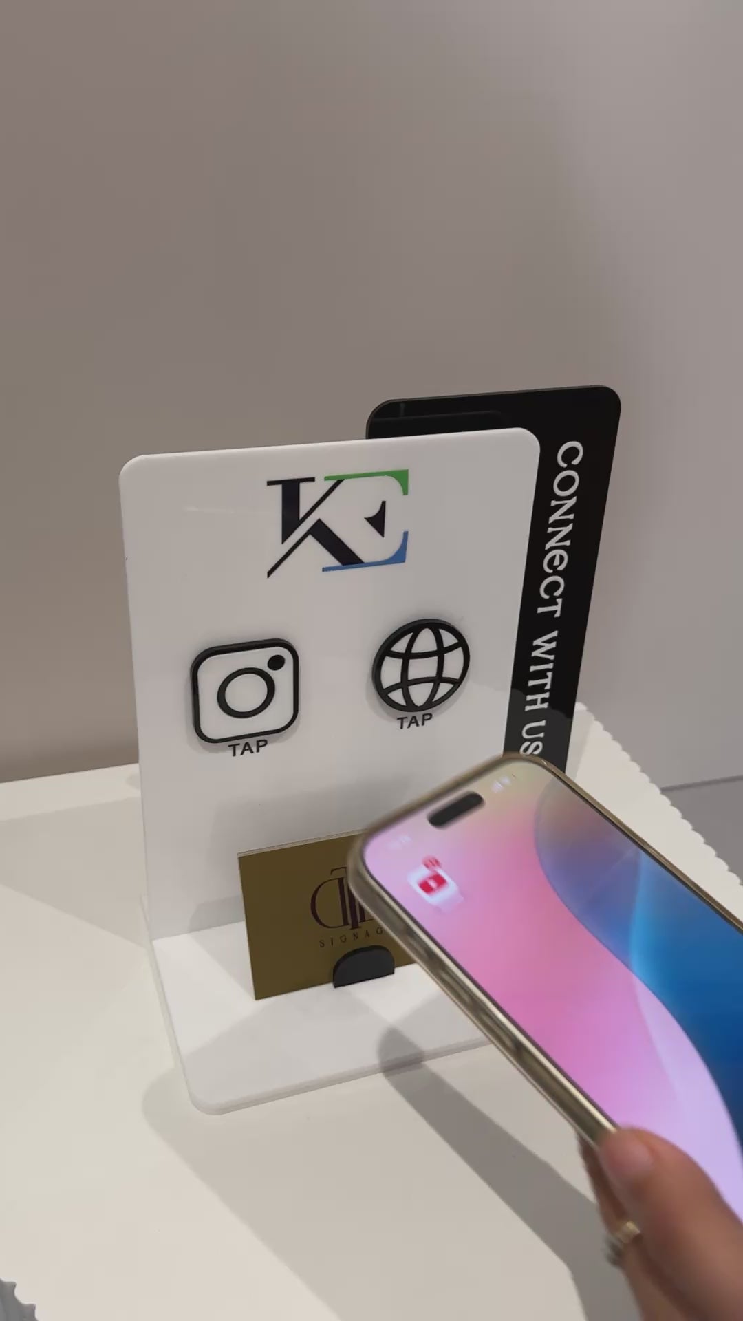 Video demonstration of a Customisable Social Media Board with Whatsapp and Instagram icons with NFC tap technology on a white surface, also have a slot of holding Business Cards, fully made of premium acrylics. 